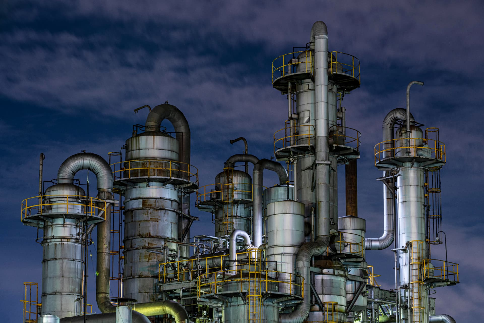 Planta industrial ao entardecer com tubulações e vasos de pressão