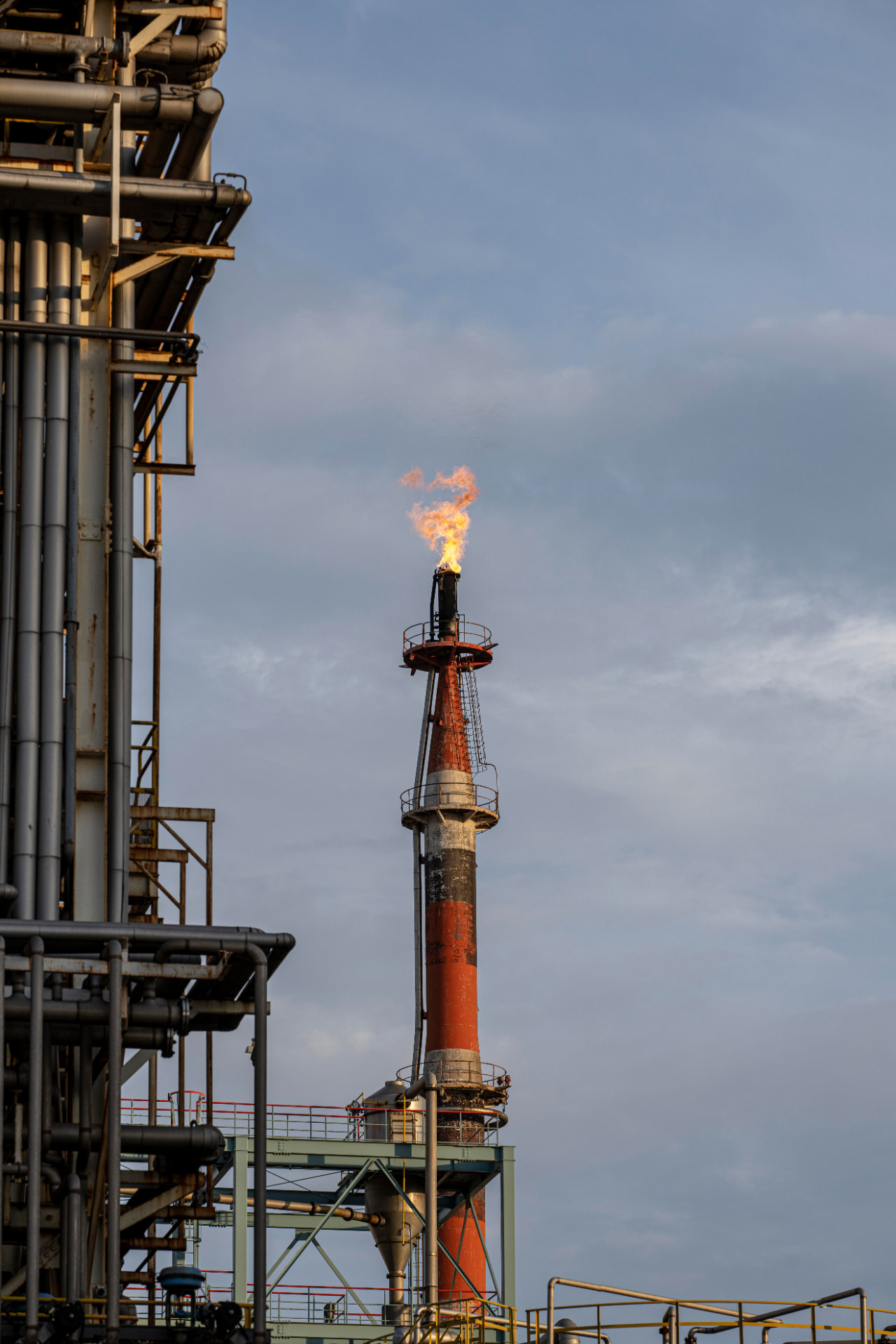 Planta industrial ao entardecer com tubulações e vasos de pressão
